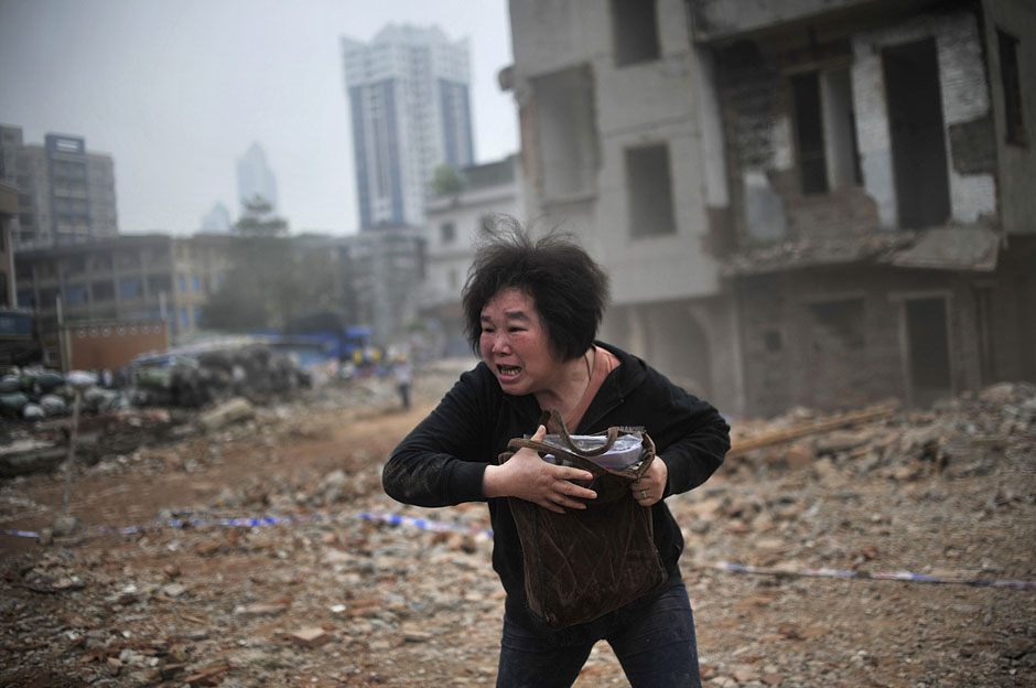 Huang Sufang reacts as she sees a part of her house being taken down by demolition workers at Yangji village in central Guangzhou city