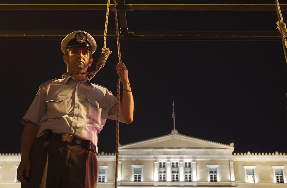 A police officer pretends to hang himself in front of the parliament during a rally in Athens