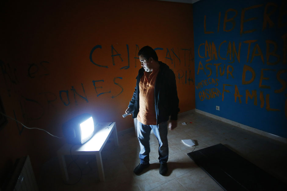 Juan Carlos Castano turns on the TV in his emptied-out bedroom as he waits for the judicial commission to carry out his eviction in Madrid