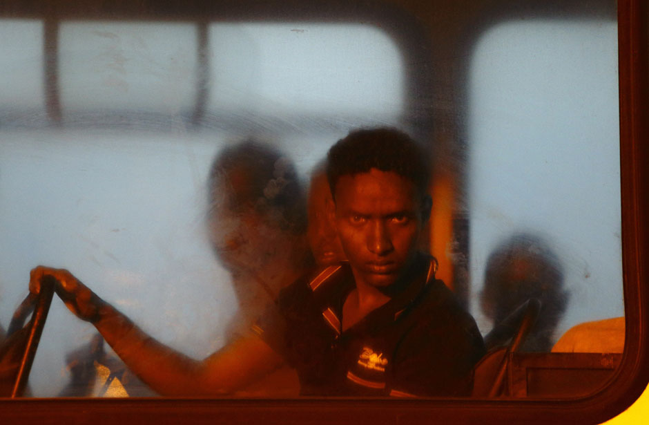 A would-be immigrant looks out of a window on a police bus after arriving at the AFM Maritime Squadron base at Haywharf in Valletta