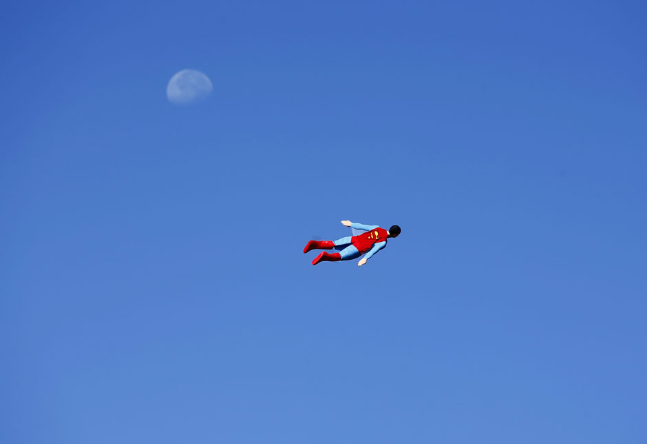 A radio-controlled Superman plane, flown by designer Otto Dieffenbach, passes the moon during a test flight in San Diego