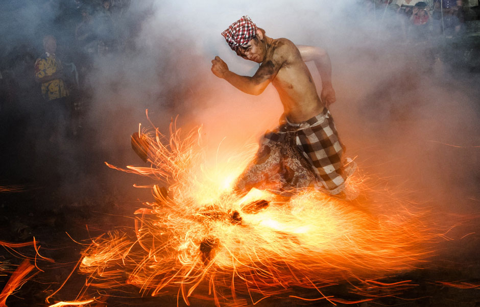A Balinese man kicks up fire during the 