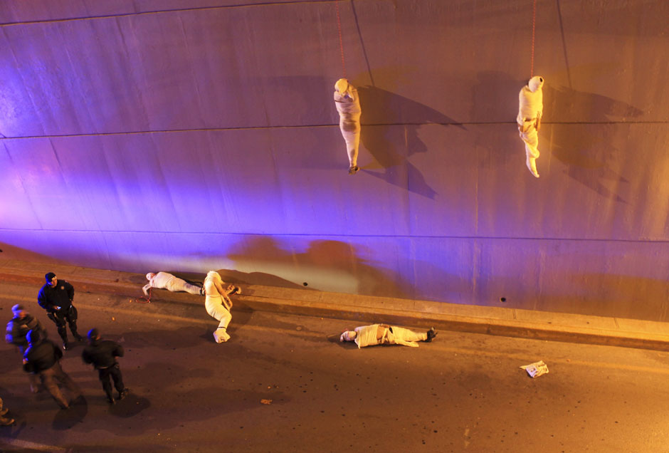 The wrapped bodies of two dead people hang from an overpass as three more dead bodies lie on the ground in Saltillo