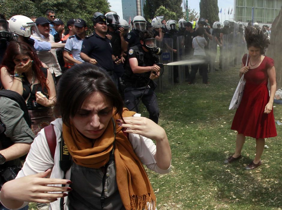 Turkish riot policeman uses tear gas during a protest in central Istanbul