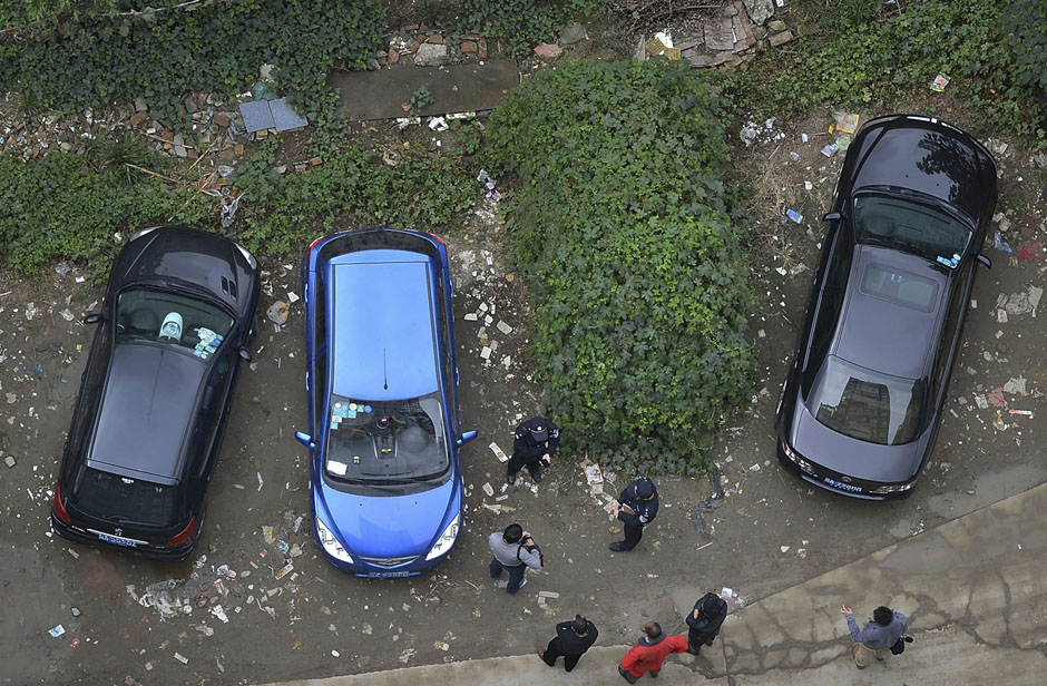 Police and bystanders look at a car which is covered with vegetation after it was left parked at a neighbourhood for more than a year, in Chengdu