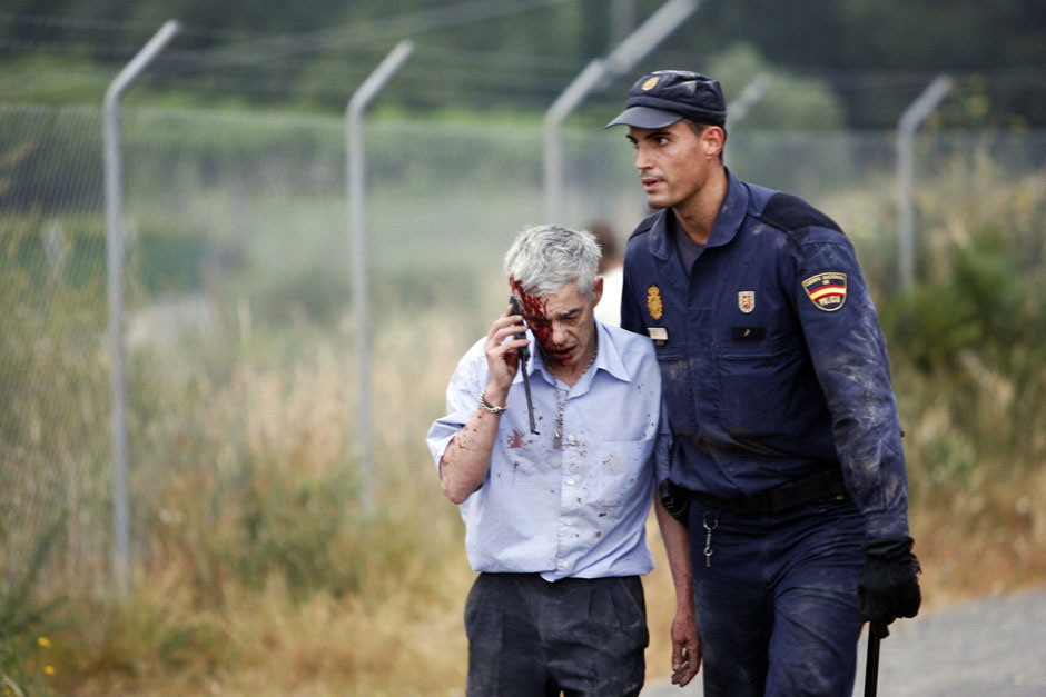 An injured man, identified by Spanish newspapers El Pais and El Mundo as the train driver Garzon, is helped by a policeman after a train crashed near Santiago de Compostela