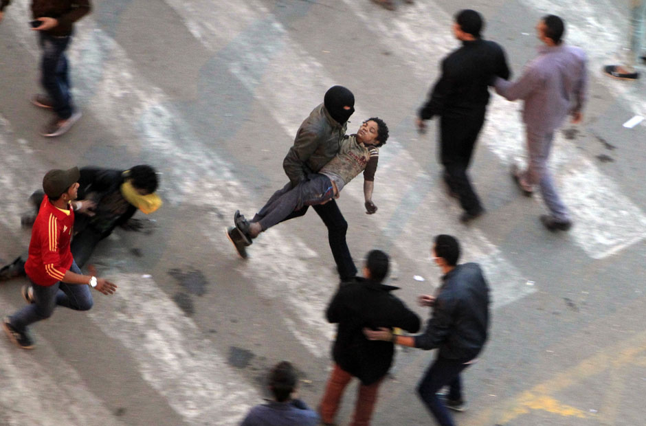 Protesters flee from tear gas fired by riot police during clashes at Qasr al-Aini Street near Tahrir Square in Cairo