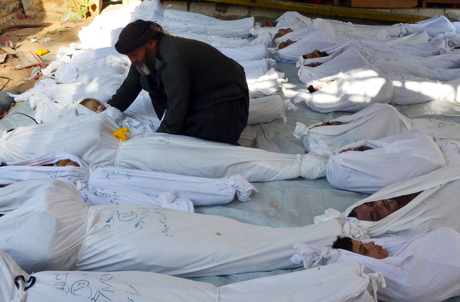 A man holds the body of a dead child among bodies of people activists say were killed by nerve gas in the Ghouta region, in the Duma neighbourhood of Damascus