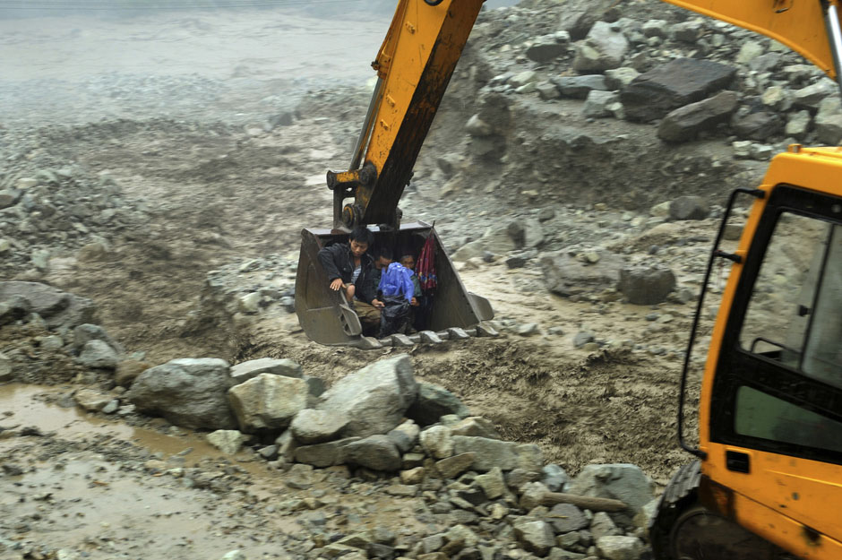 An excavator moves villagers away from a flooded area during heavy rainfall in Yingxiu