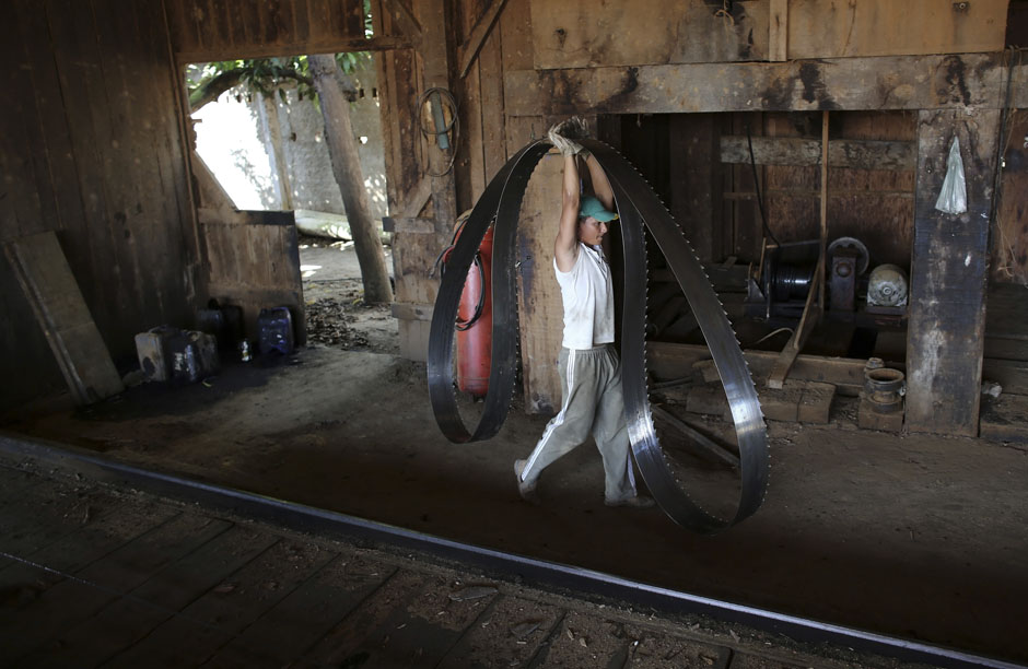 A worker carries a blade at a sawmill that processes trees illegally logged from the Amazon jungle near Morais Almeida