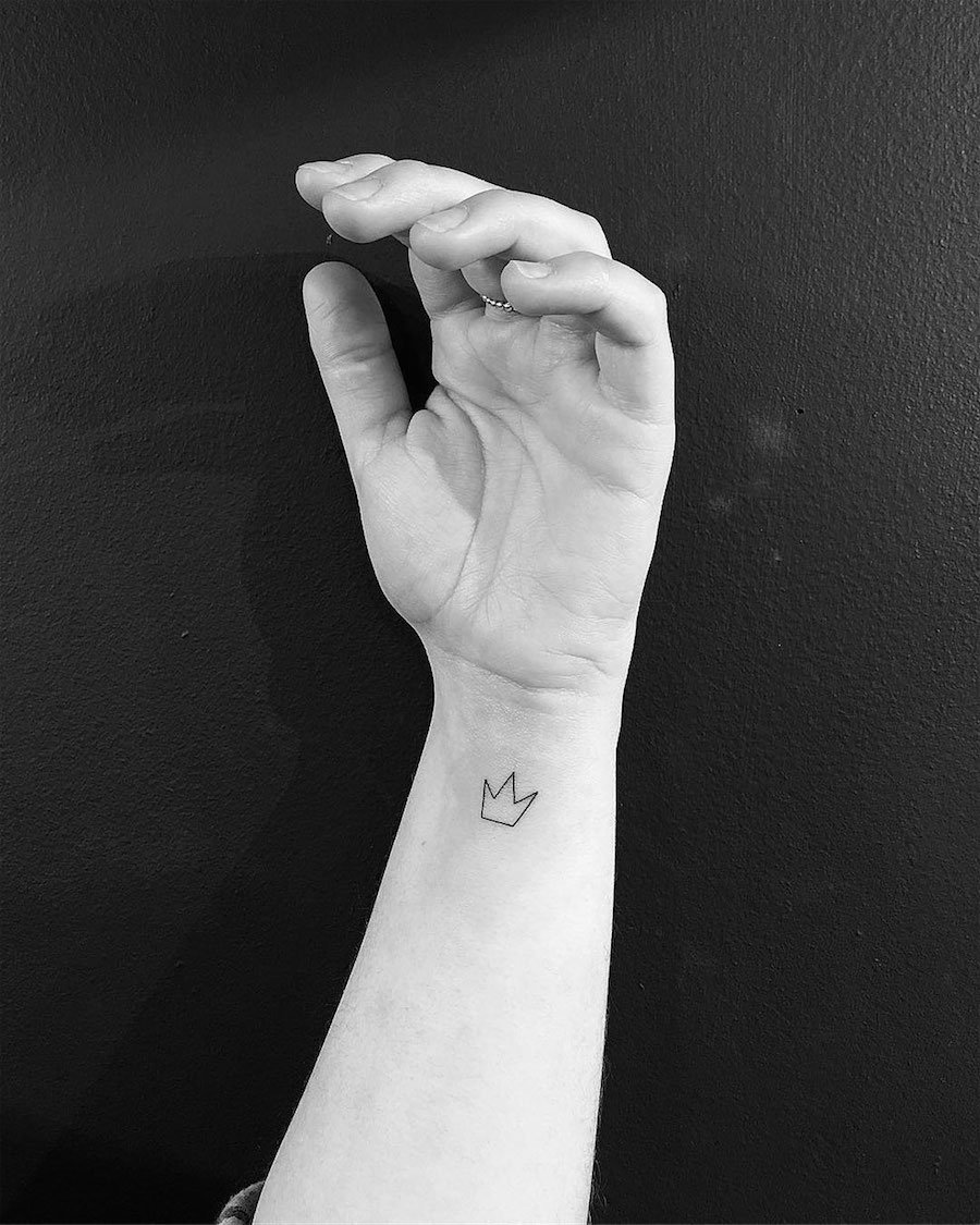 Minimalist crown tattoo on the wrist.