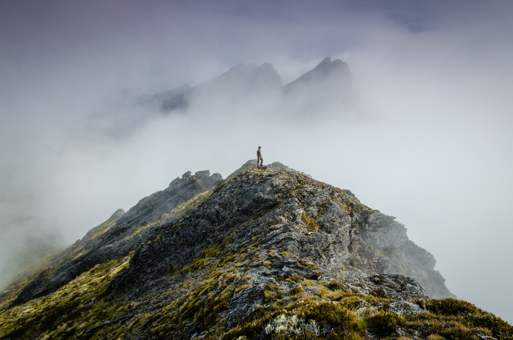 Person on top of misty rocky mountain