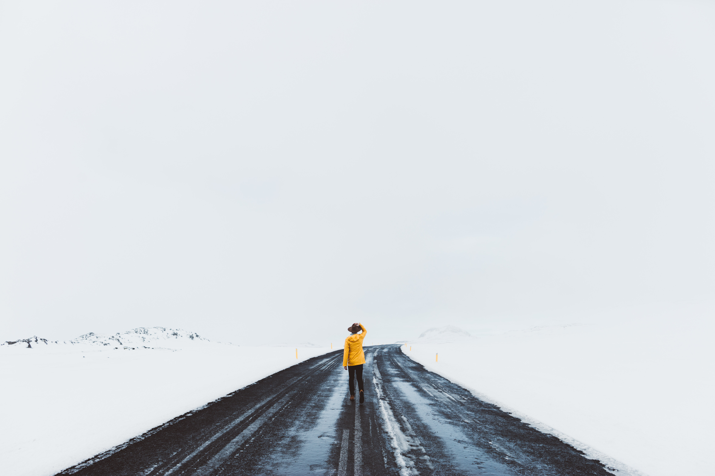 Rear view of man standing in road on snow covered landscape