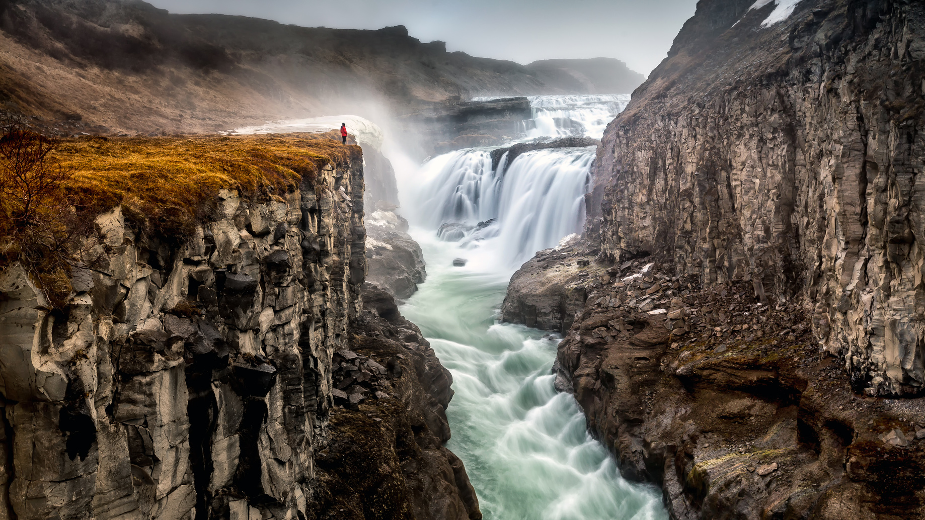 Man watching waterfall from cliff