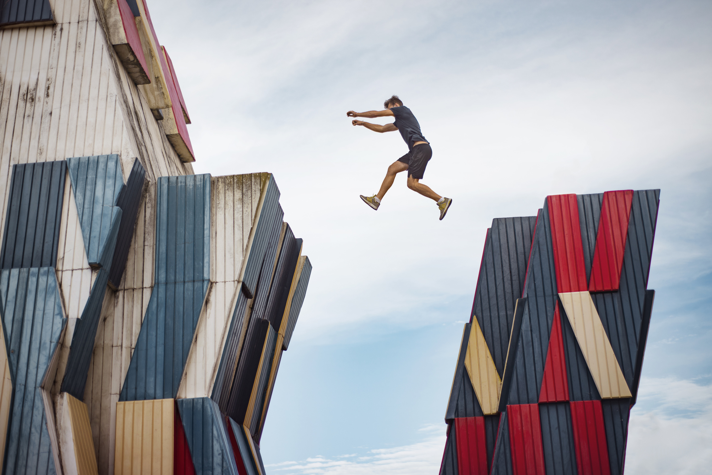 Low angle view of man jumping over buildings against sky