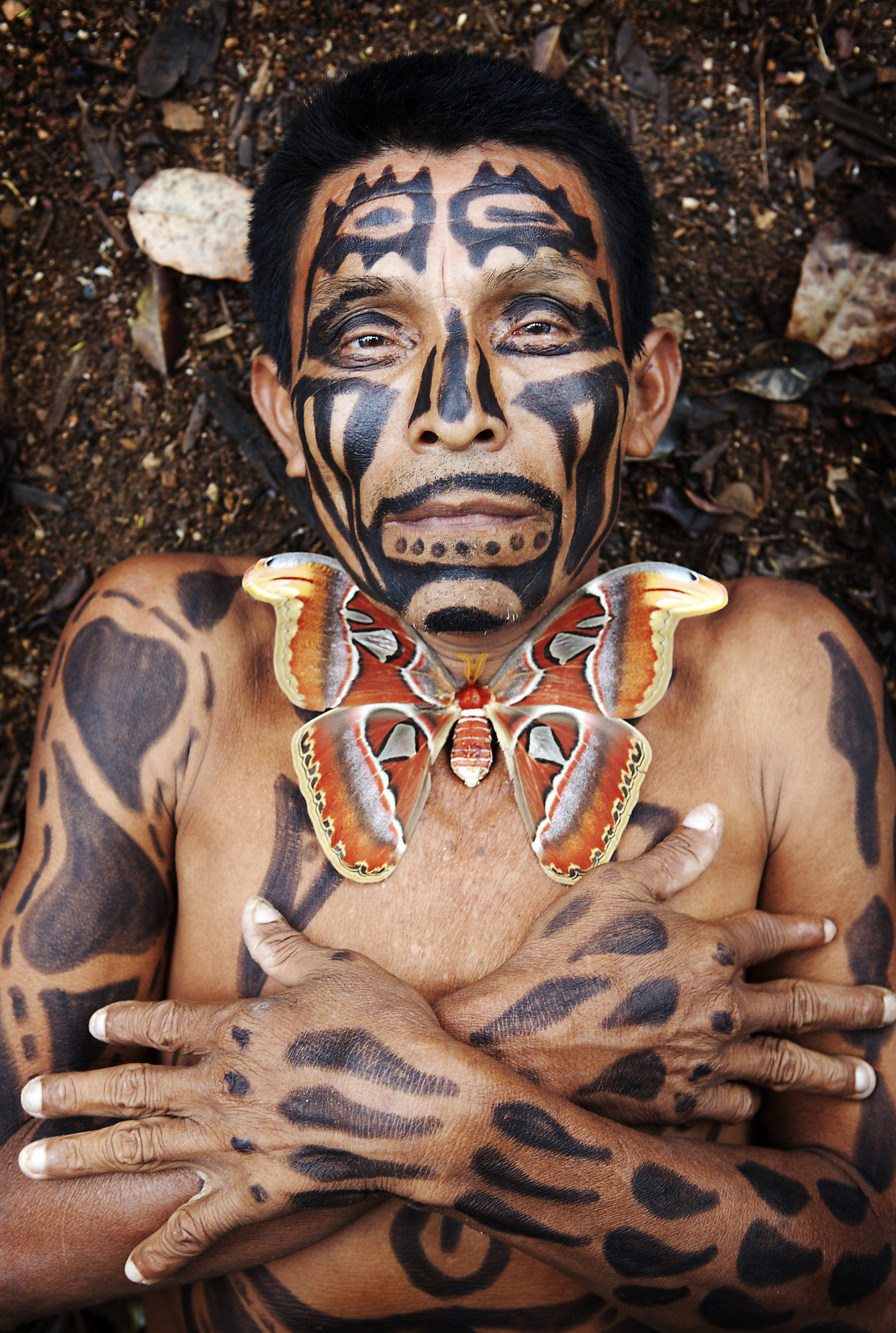 Hispanic man with painted body laying in dirt, Lago Izabal, Guatemala