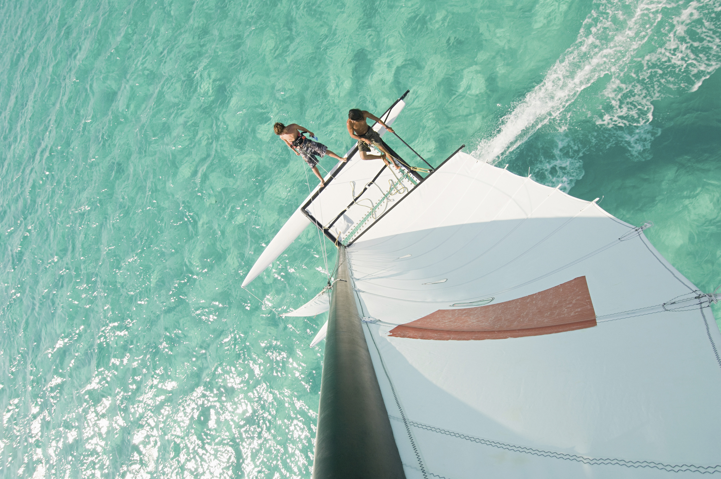 High angle view of men hoisting rigging on sailboat