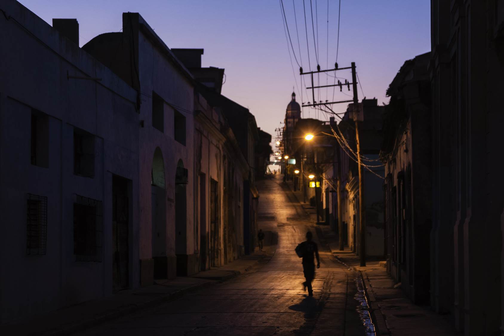 Pedestrian walking on Santiago de Cuba street at night, Santiago, Cuba
