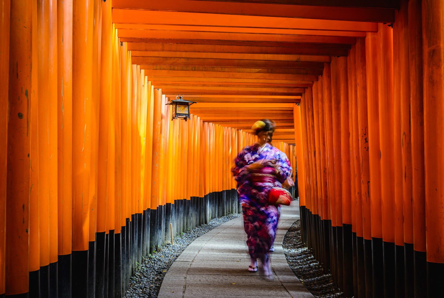 Woman in kimono walking under wooden pillars