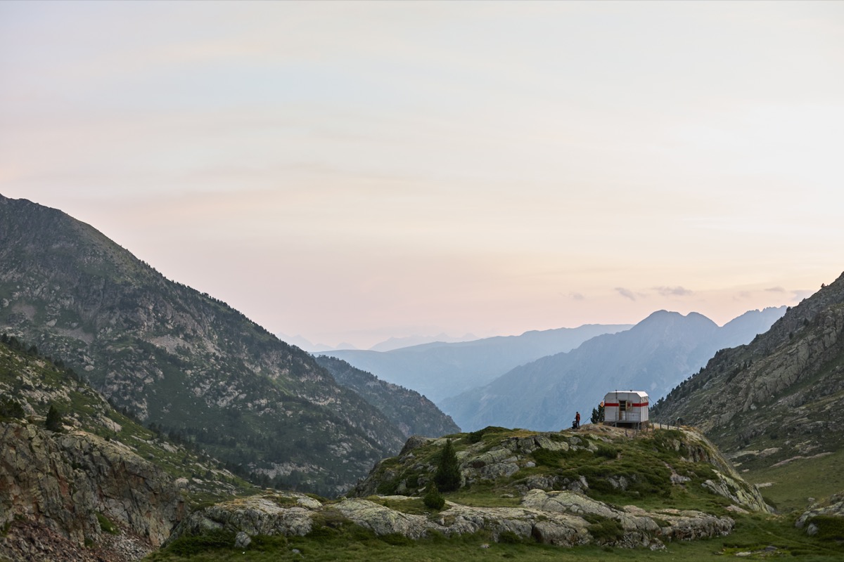 Mountain landscape with little cabin and two people silhouettes