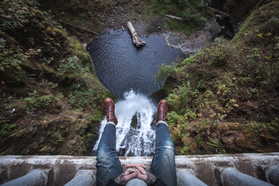 Legs and feet of man through railings over waterfall