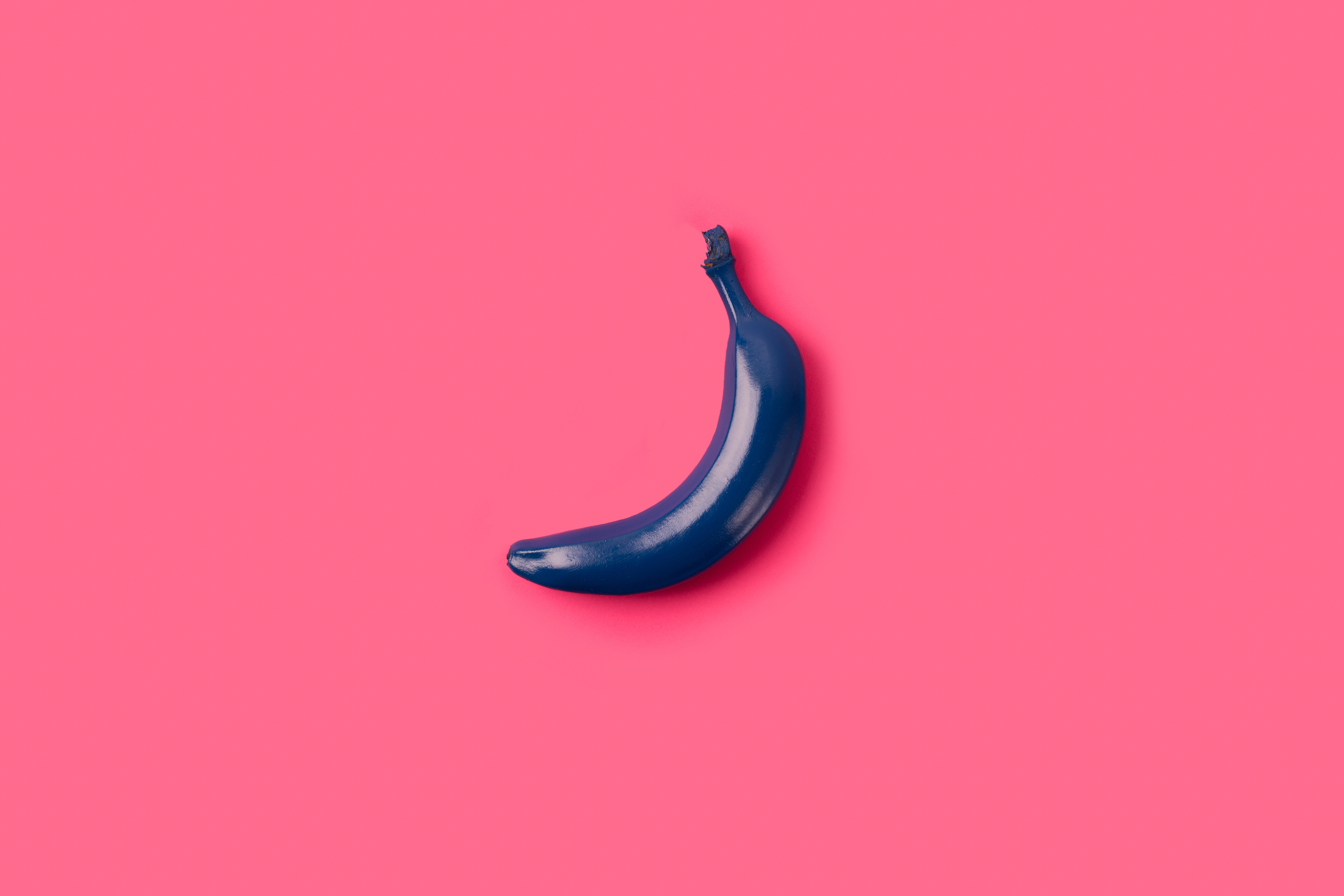 Blue banana over a pink background. Top view, minimal concept.